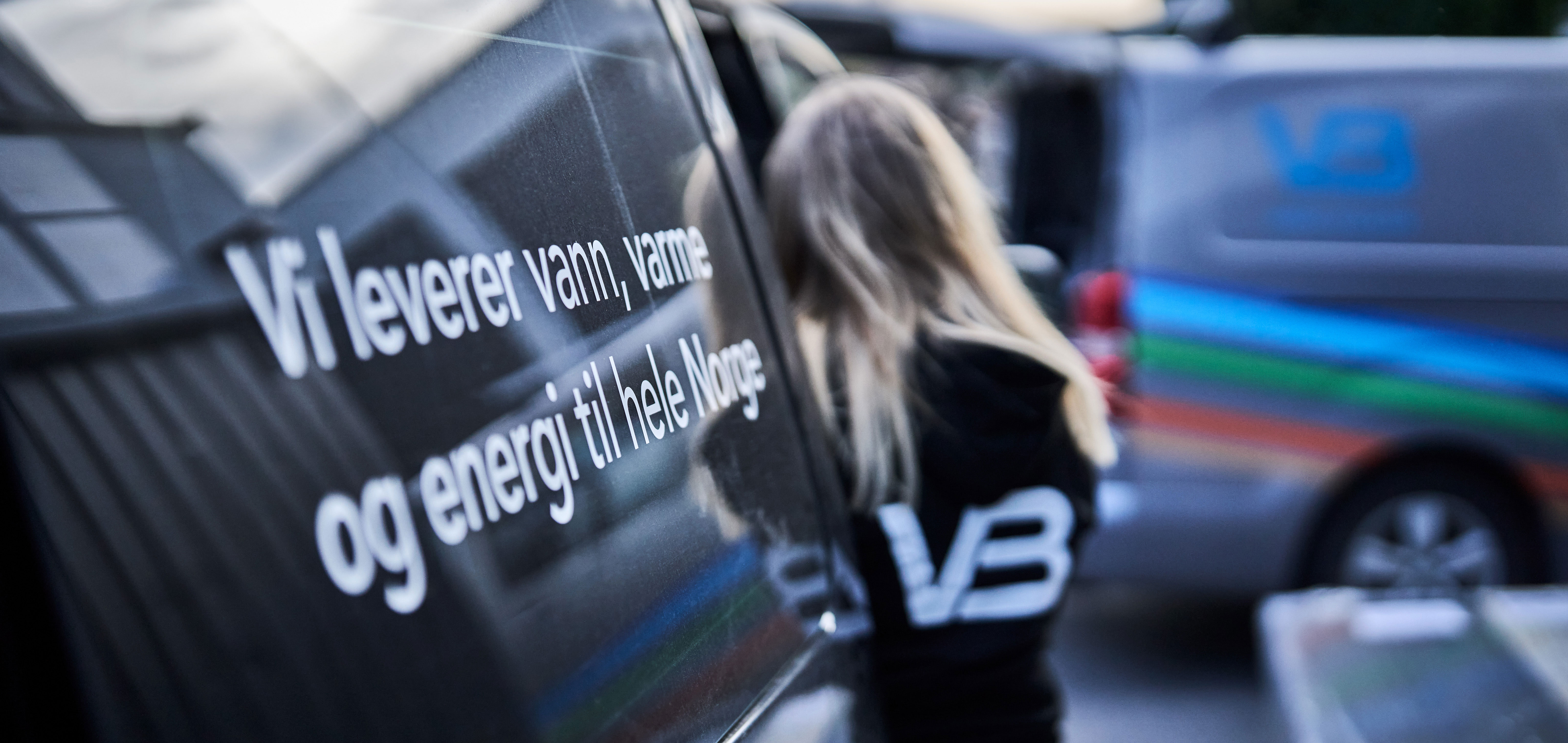 VB-rørlegger ved en bil med VB-profilering: Vi leverer vann, varme og energi til hele Norge.